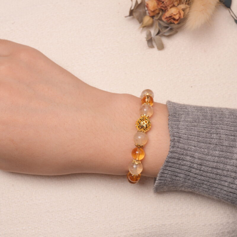 A model wearing the Citrine bracelet on their wrist. The bracelet showcases the rich golden hues of the Citrine beads, with a unique golden accent bead at the center, adding a touch of elegance.
