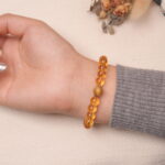 A model wearing the Citrine bracelet on their wrist. The bracelet showcases the rich golden hues of the Citrine beads, with a unique golden accent bead at the center, adding a touch of elegance.