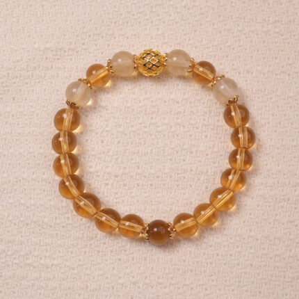 A Citrine bracelet made with smooth, golden Citrine beads. The bracelet features a central golden accent bead, enhancing its luxurious and radiant look.