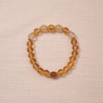 A Citrine bracelet made with smooth, golden Citrine beads. The bracelet features a central golden accent bead, enhancing its luxurious and radiant look.