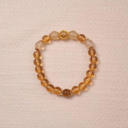 A Citrine bracelet made with smooth, golden Citrine beads. The bracelet features a central golden accent bead, enhancing its luxurious and radiant look.