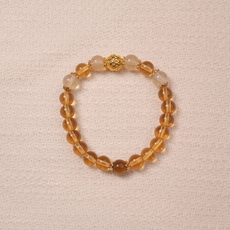 A Citrine bracelet made with smooth, golden Citrine beads. The bracelet features a central golden accent bead, enhancing its luxurious and radiant look.