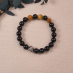 The Obsidian and Tiger Eye bracelet placed on a soft fabric background, with the natural stones creating an earthy, grounding vibe.