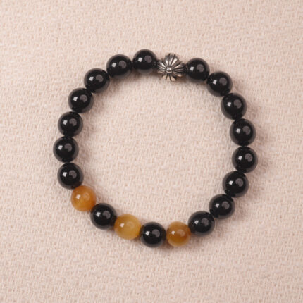 A close-up of the Obsidian and Tiger Eye bracelet, featuring black Obsidian beads paired with golden Tiger Eye stones, finished with a silver flower charm.