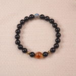 A close-up of an Obsidian, Citrine, and Moonstone bracelet. The dark black Obsidian beads, golden Citrine beads, and iridescent Moonstone bead create a stunning contrast and a powerful energy combination.