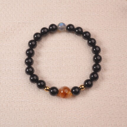 A close-up of an Obsidian, Citrine, and Moonstone bracelet. The dark black Obsidian beads, golden Citrine beads, and iridescent Moonstone bead create a stunning contrast and a powerful energy combination.