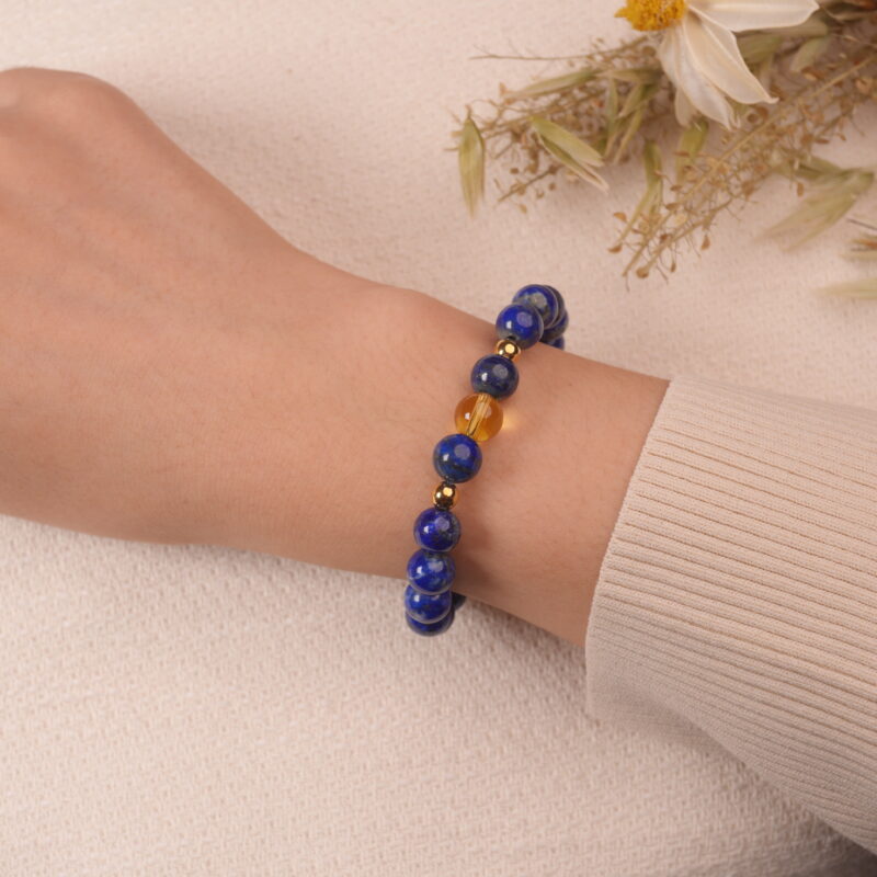 A hand wearing the Lapis Lazuli and Citrine bracelet. The combination of deep blue and vibrant yellow gemstones creates an eye-catching and energizing accessory.