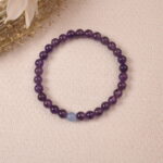 The Amethyst and Aquamarine bracelet placed on a soft fabric background, surrounded by delicate natural elements. The bracelet's colors evoke a sense of serenity and tranquility.