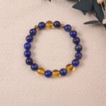 The Lapis Lazuli and Citrine bracelet placed on a soft fabric background with natural elements. The combination of deep blue and golden hues evokes a sense of luxury and tranquility.