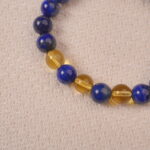 A detailed close-up of the Lapis Lazuli and Citrine bracelet, showcasing the polished gemstones and the gold spacer beads. The vivid blue and yellow colors create a harmonious contrast.