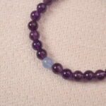 A detailed close-up of the Amethyst and Aquamarine bracelet, showcasing the smooth purple Amethyst beads and the pale blue Aquamarine bead. The colors blend harmoniously, creating a peaceful aesthetic.