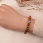 A hand wearing the Yellow Chalcedony and White Chalcedony bracelet, showcasing the warm golden and soft white beads with a silver spacer. The bracelet adds a sophisticated touch to the wrist, making it a versatile accessory for various occasions.