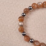 A detailed close-up of the Peach Moonstone bracelet, highlighting the polished beads and the silver spacer beads. The subtle shine of the gemstones adds a touch of elegance to the bracelet.