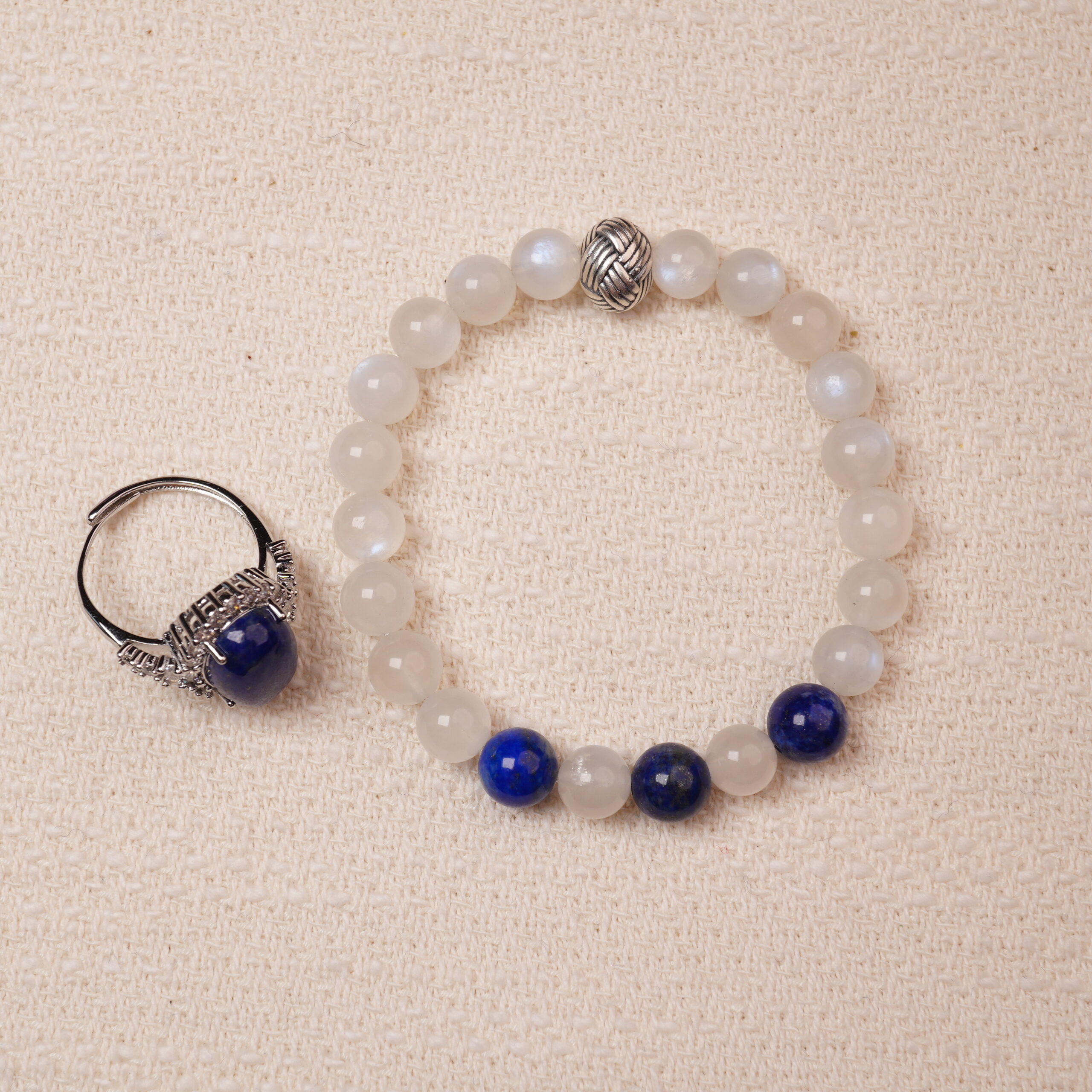 lapis-lazuli-moonstone-bracelet-ring-set-main A stunning set featuring a Lapis Lazuli and Moonstone bracelet paired with a Lapis Lazuli ring. The bracelet combines smooth Moonstone beads with deep blue Lapis Lazuli, highlighted by intricate silver accents. The matching ring complements the bracelet with a bold Lapis Lazuli centerpiece encircled by sparkling details, creating a harmonious and elegant look.