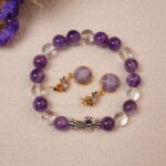 The Amethyst and Quartz bracelet and purple embroidered earrings placed next to flowers, bringing a touch of elegance and tranquility to any setting.
