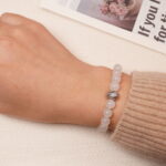 A model wearing the Moonstone and Lapis Lazuli bracelet on their wrist, showing the smooth, glowing moonstone beads and the deep blue lapis lazuli stones. The bracelet adds an elegant touch to the overall look.