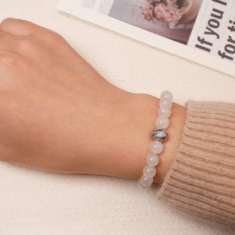 A model wearing the Moonstone and Lapis Lazuli bracelet on their wrist, showing the smooth, glowing moonstone beads and the deep blue lapis lazuli stones. The bracelet adds an elegant touch to the overall look.