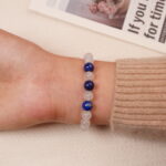 A model wearing the Moonstone and Lapis Lazuli bracelet on their wrist from the back view, showing the smooth texture of the beads and the stylish silver accent bead.