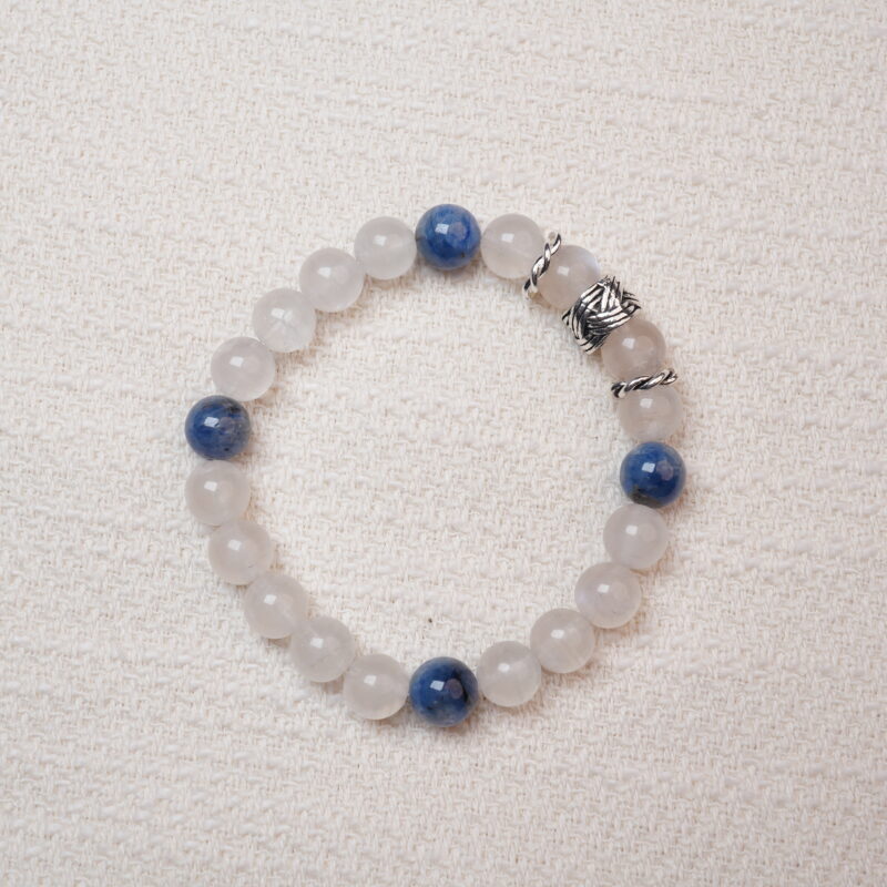 Moonstone and kyanite bracelet photographed under soft daylight on a pink background, highlighting the milky white glow of moonstone and the deep blue tones of kyanite.