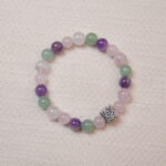 A beaded bracelet made of rose quartz, amethyst, and green aventurine with a silver rose charm.