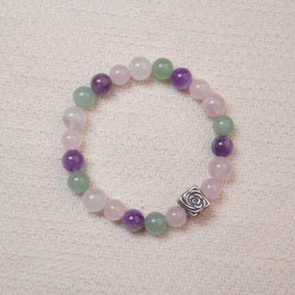 A beaded bracelet made of rose quartz, amethyst, and green aventurine with a silver rose charm.