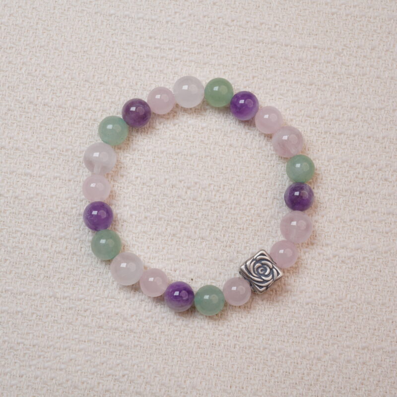 A beaded bracelet made of rose quartz, amethyst, and green aventurine with a silver rose charm.