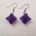Close-up of the Amethyst Merkaba earrings, highlighting the intricate details of the geometric shape and the vibrant purple hue of the Amethyst.