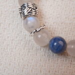 Close-up of the Moonstone and Kyanite bracelet, showing the smooth texture of the beads and the silver accent, designed to bring peace and balance.