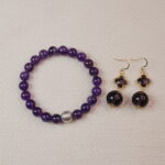 A stunning set featuring a vibrant Amethyst bracelet paired with matching Amethyst earrings. The bracelet is adorned with a silver accent bead, while the earrings showcase elegant Amethyst stones. Together, they create a sophisticated and calming accessory combination.