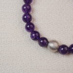 Close-up of the Amethyst bracelet, showing the rich purple color of the beads and the intricate silver accent bead that adds a touch of elegance to the piece.