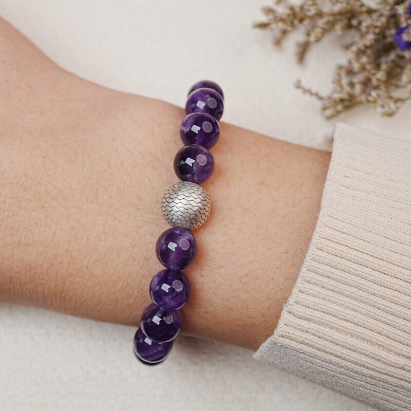 Amethyst bracelet with a silver bead worn on the wrist, showing the front view of the bracelet.