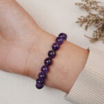 Side view of the amethyst bracelet worn on the wrist, showing polished purple beads.