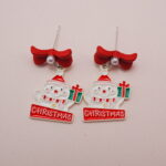 Close-up of Santa Claus earrings with a red bow, Christmas gifts, and a festive design.