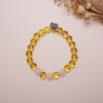 Yellow citrine and rose quartz bracelet with silver heart charm displayed in a styled flat lay.