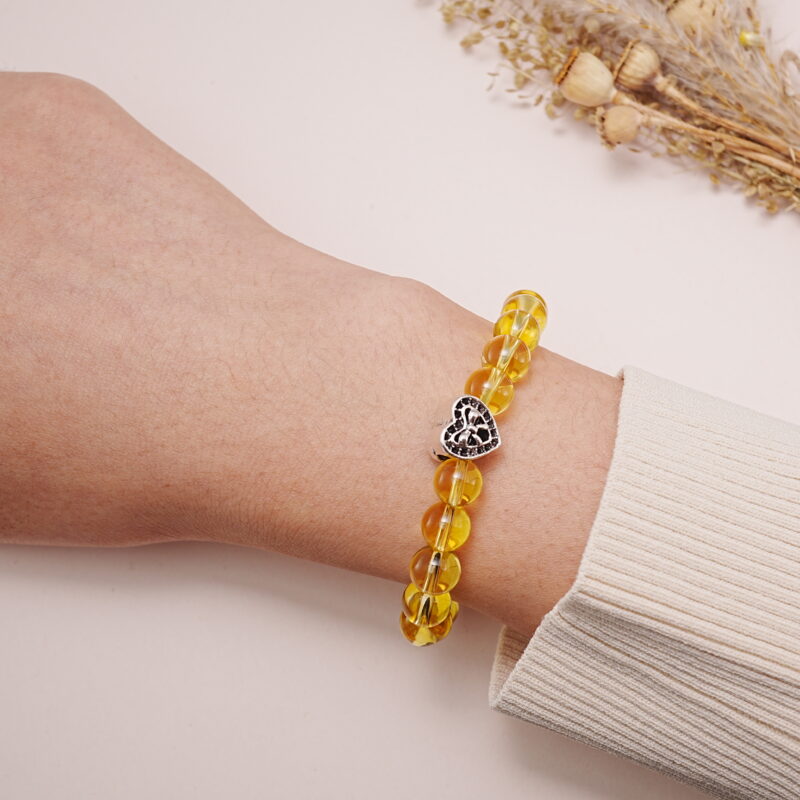 Yellow citrine and rose quartz bracelet with heart charm worn on wrist.