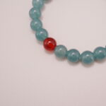 Close-up of the green chalcedony bracelet with the striking carnelian accent, showcasing the smooth texture and vibrant colors of the stones.