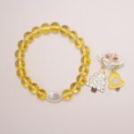 A bright yellow quartz bead bracelet with a white pearl centerpiece, paired with yellow bell and Christmas tree bow earrings.
