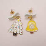 Detailed view of the yellow bell and Christmas tree bow earrings with sparkling elements.