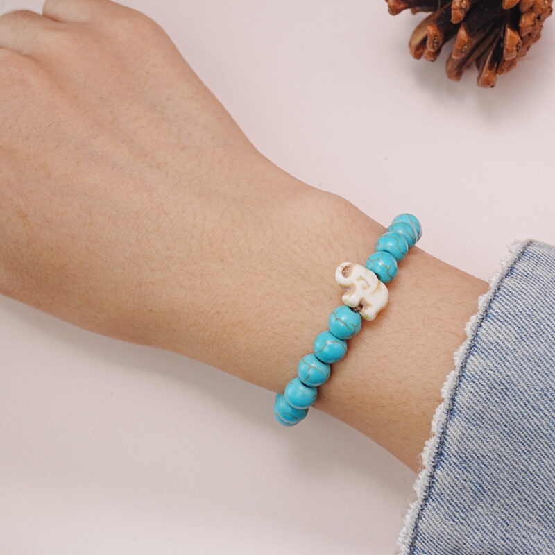 Person wearing a turquoise bracelet with a white skull charm, showcasing the style on the wrist.