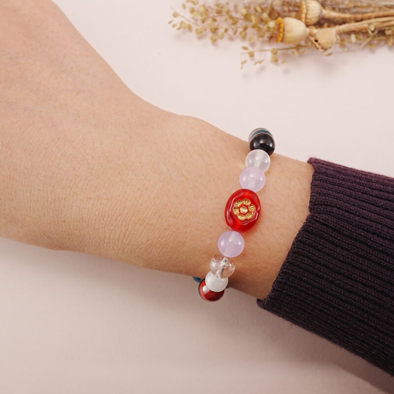 A model wearing the Multi-Gemstone bracelet on their wrist. The colorful gemstones and intricate charm add a bold and stylish statement to the outfit.