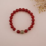 The Carnelian and Green Chalcedony bracelet resting on a soft background, highlighting the contrast of the vibrant red and green gemstones and the elegant design.