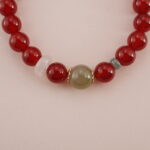 Close-up of the Carnelian and Green Chalcedony beads, showcasing their smooth surface and rich colors. The gold spacer bead adds a sophisticated touch to the bracelet’s design.