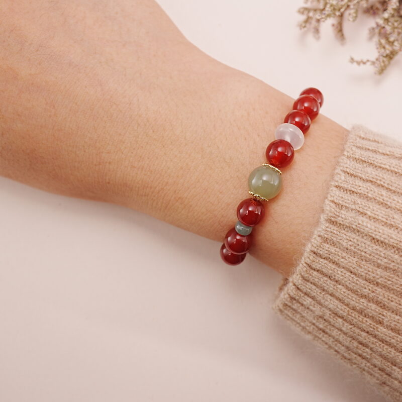 A model wearing the Carnelian and Green Chalcedony bracelet on their wrist. The bright red and green colors complement each other beautifully, creating a bold yet harmonious look.