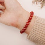 A model wearing the Carnelian and Green Chalcedony bracelet on their wrist. The bright red and green colors complement each other beautifully, creating a bold yet harmonious look.
