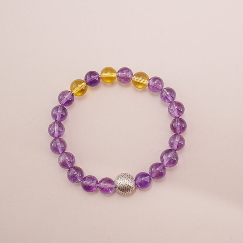 A stunning Amethyst and Citrine bracelet featuring a blend of deep purple and golden yellow gemstones, accented with a silver bead. This bracelet embodies positive energy and balance, making it perfect for bringing harmony into your life.