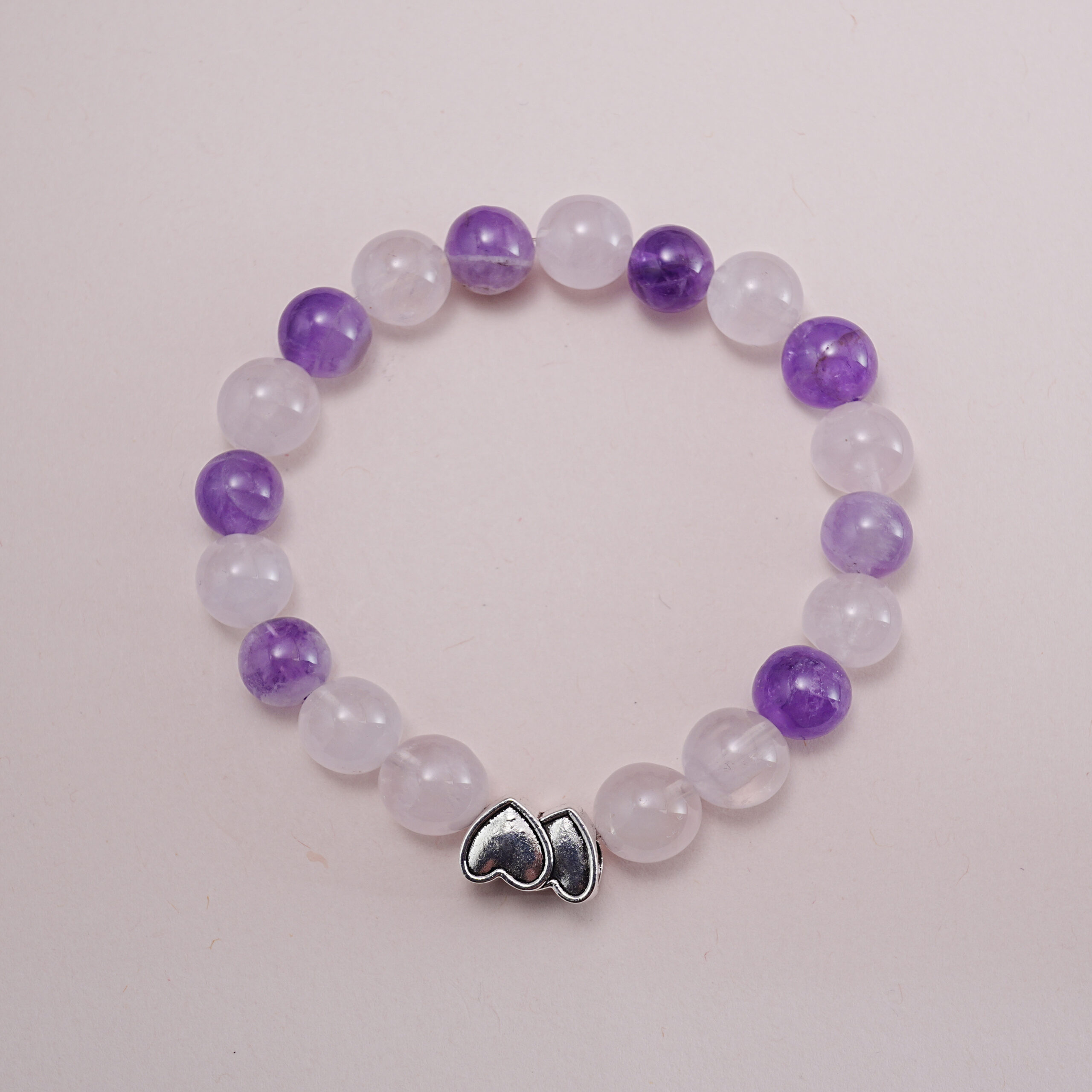 amethyst-rose-quartz-heart-bracelet-main.jpg Amethyst and rose quartz bracelet with silver heart charm – main product image