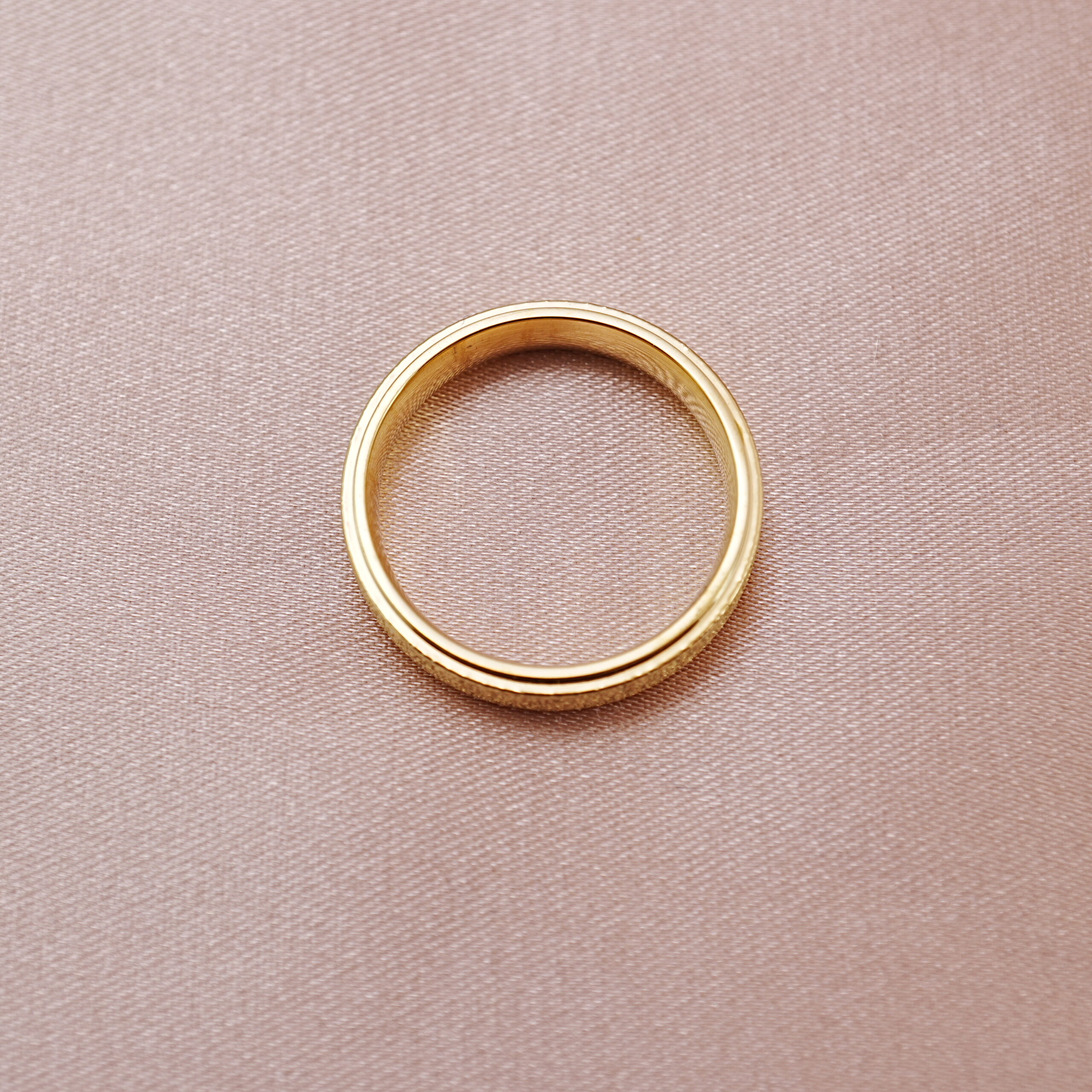 stainless-steel-textured-band-ring-main.jpg Textured stainless steel band ring displayed on a soft fabric background.