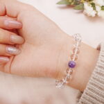 Model wearing clear quartz bracelet with amethyst beads – front wrist view.