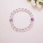 Flatlay image of clear quartz bracelet featuring two purple amethyst beads.