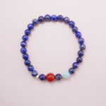 Lapis lazuli bracelet with a carnelian accent bead and aquamarine charm displayed on a soft background.